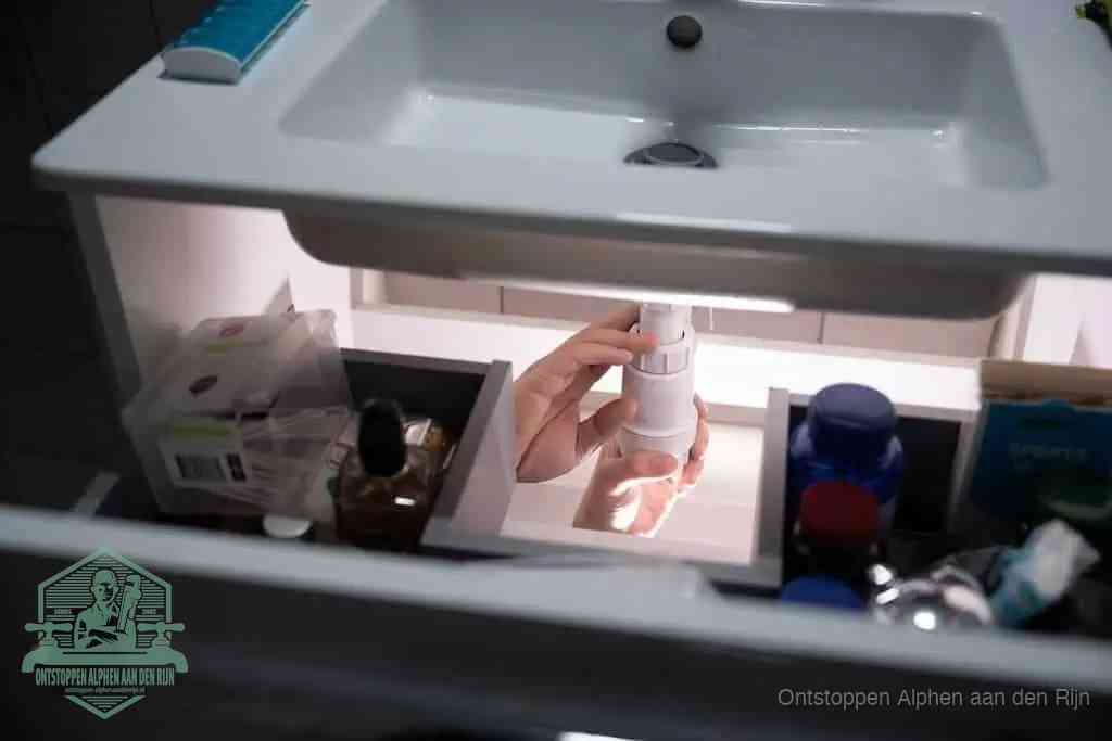 Een pompfles met zeep boven een wastafel, de heet water en afwasmiddel-methode om een vetprop in de afvoer los te maken in Alphen aan den Rijn