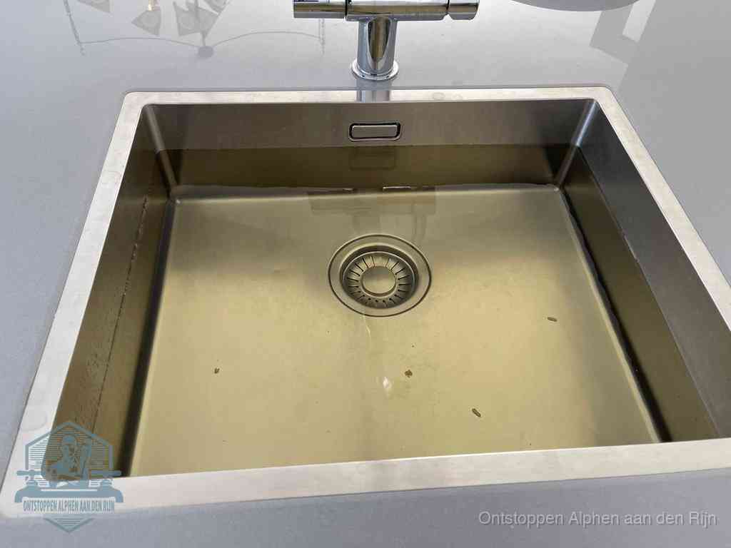 Stilstaand water in een rvs spoelbak dat niet wegloopt, een duidelijk signaal van een gootsteenverstopping in Alphen aan den Rijn