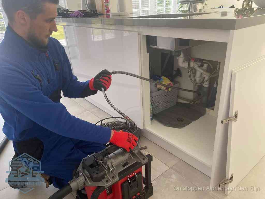 Een monteur reinigt de keukenafvoer grondig met een veermachine om terugkerende gootsteenverstoppingen te voorkomen in Alphen aan den Rijn