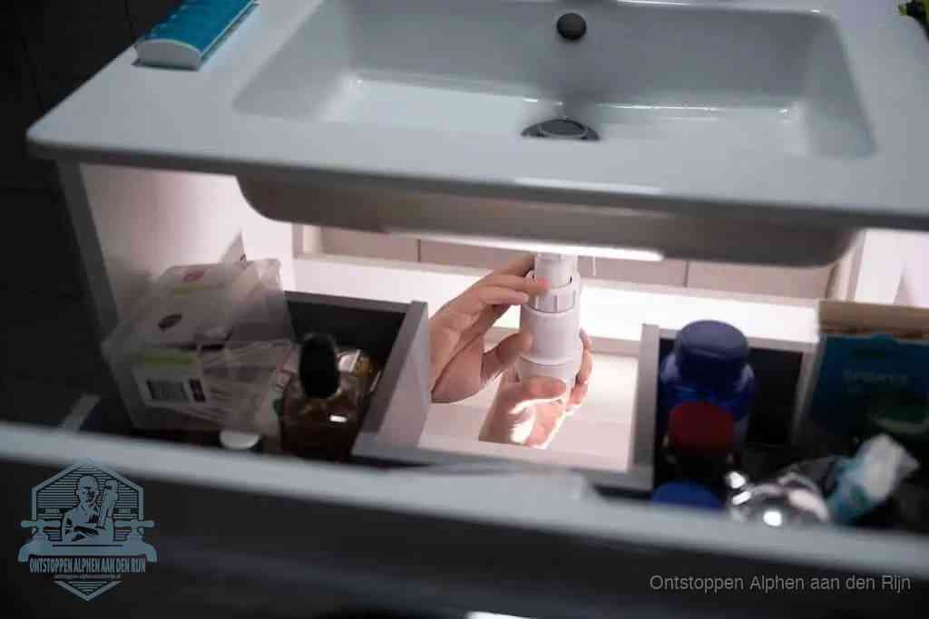 Een pompfles met zeep boven een wastafel in de toiletruimte, de warm water en afwasmiddel-methode om de wc te ontstoppen in Alphen aan den Rijn