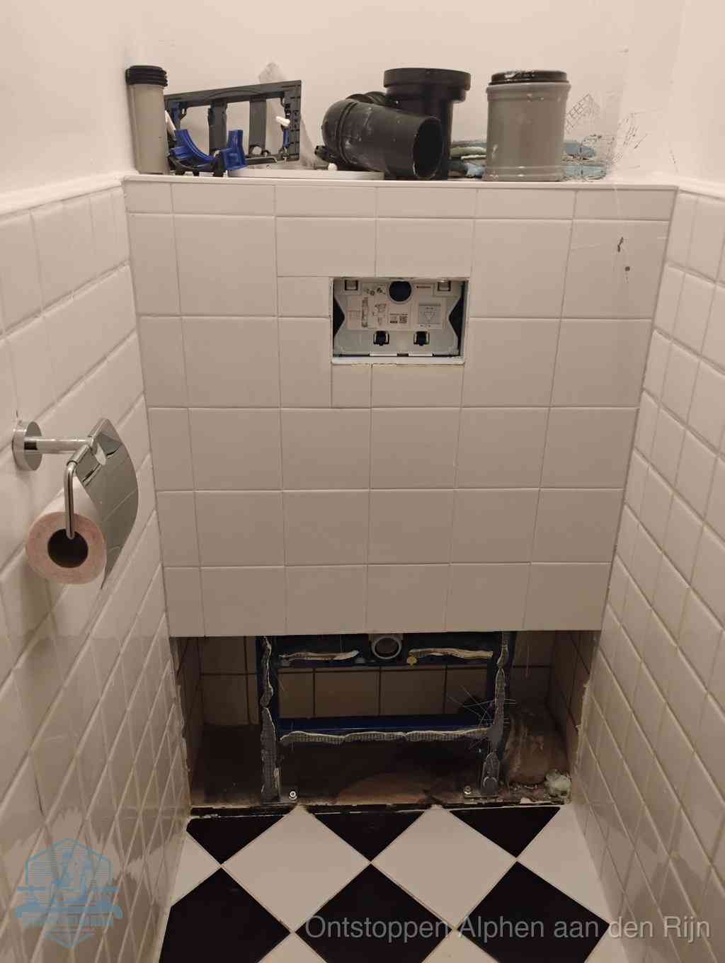 Een toiletruimte waar het hangtoilet en de inbouwreservoir-onderdelen zijn vrijgelegd voor onderhoud, periodiek nazicht voorkomt een wc-verstopping in Alphen aan den Rijn