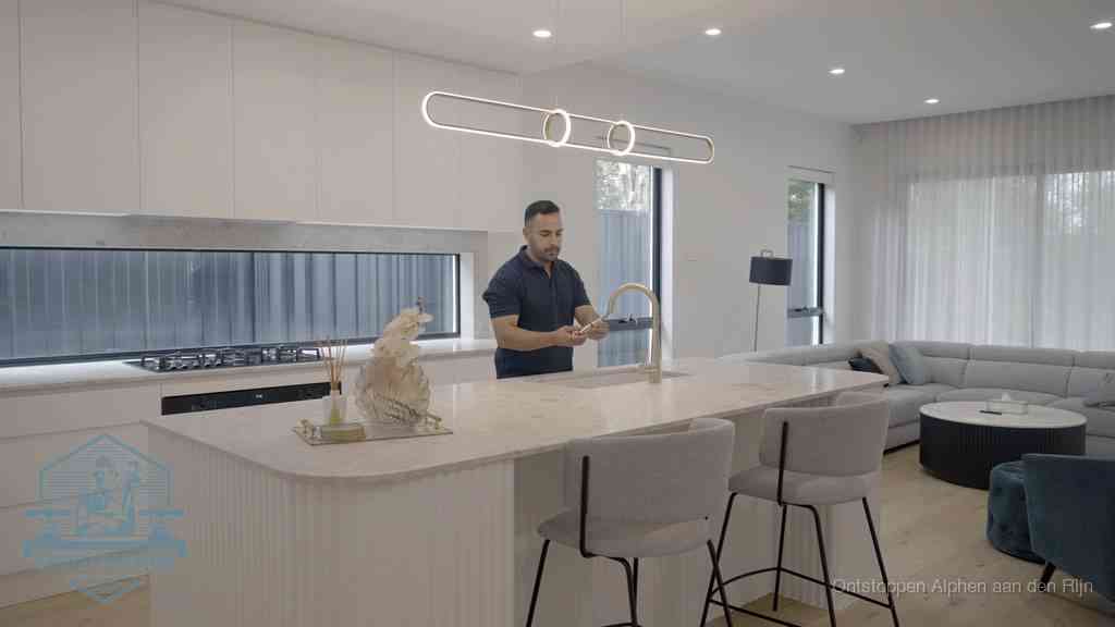 Een bewoner bij de keukenspoelbak die zelf aan de slag gaat met een verstopte gootsteen in Alphen aan den Rijn